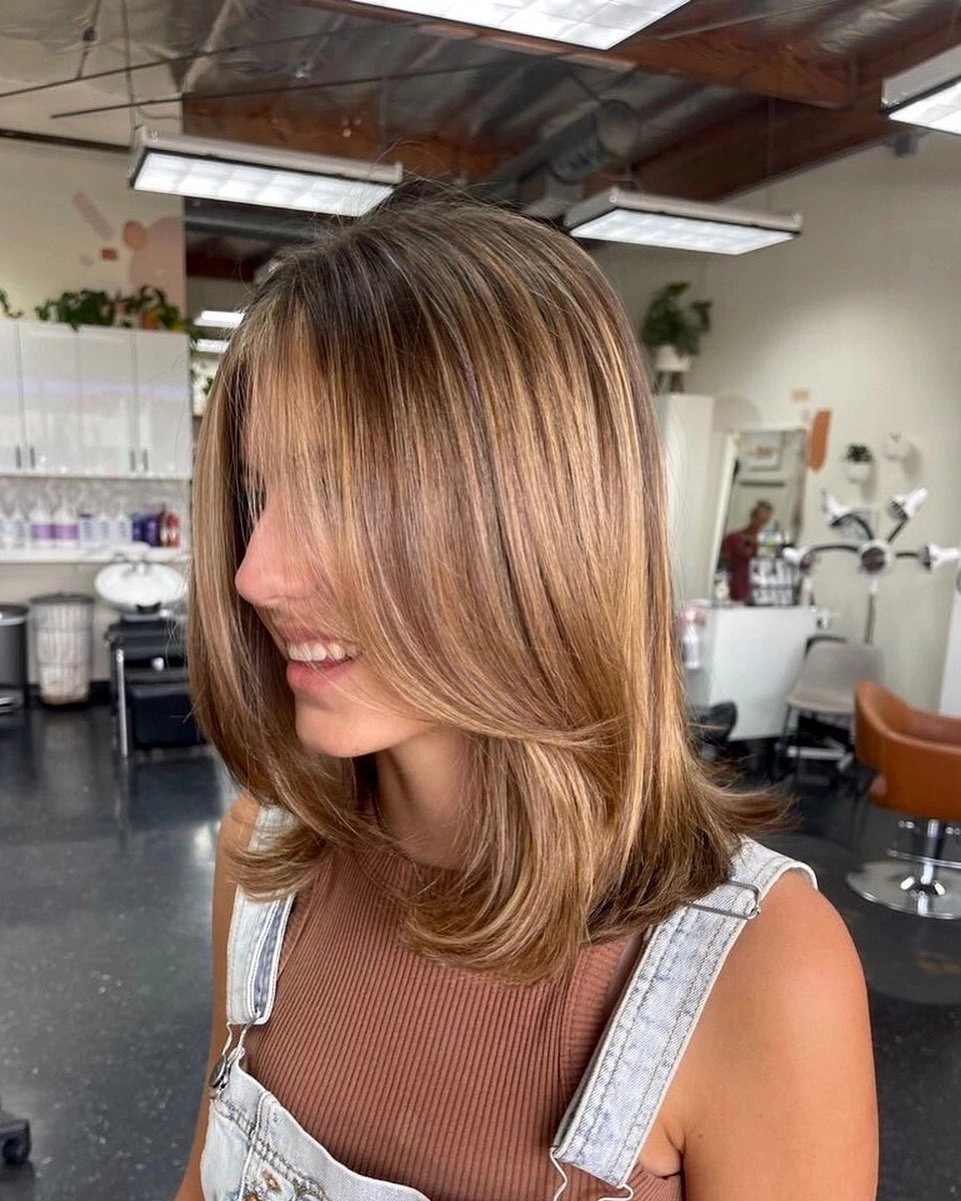 Textured warm brown shoulder-length lob with side-swept fringe and curved ends