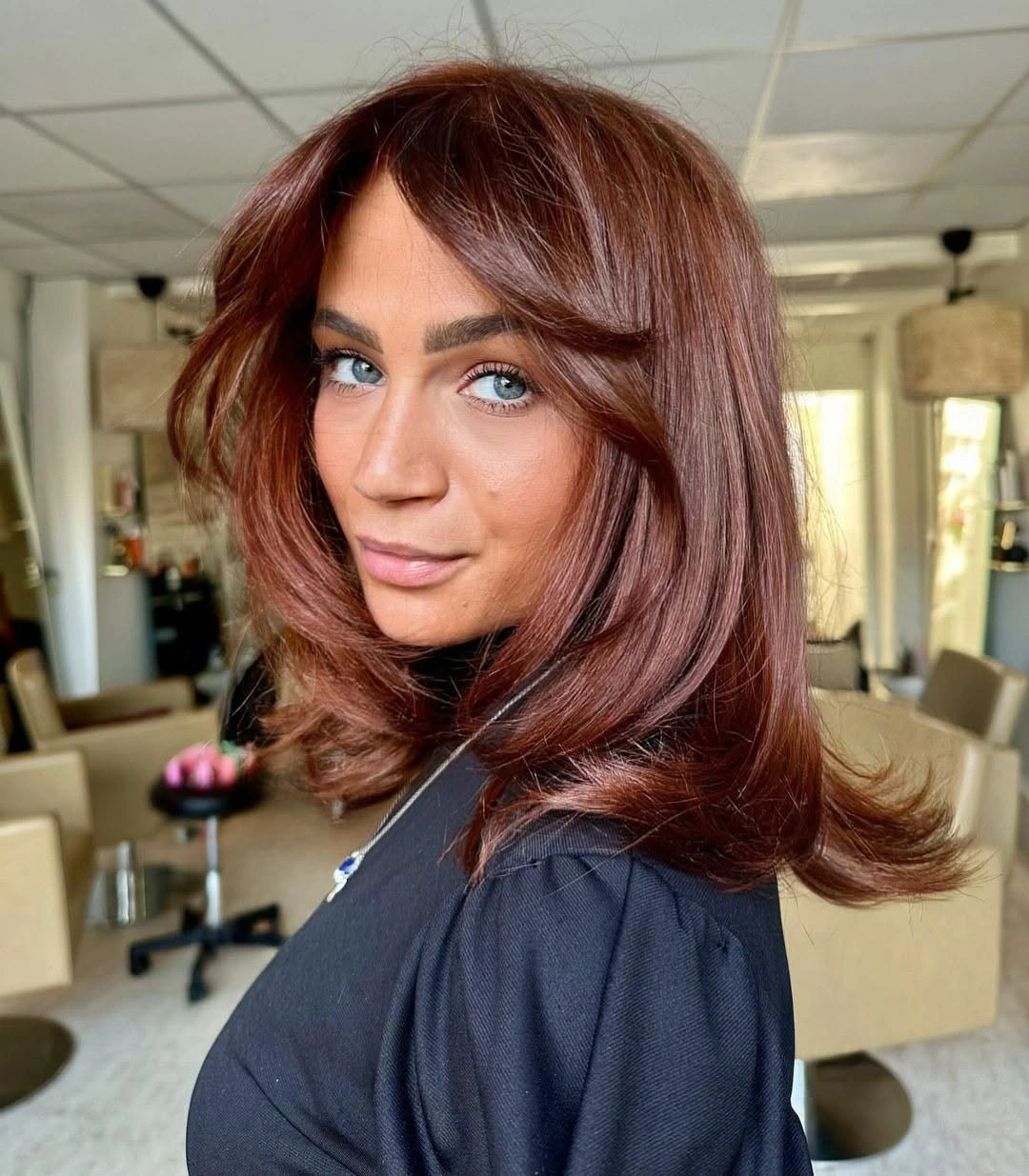 Auburn shoulder-length layered haircut with long side fringe and feathered outward ends