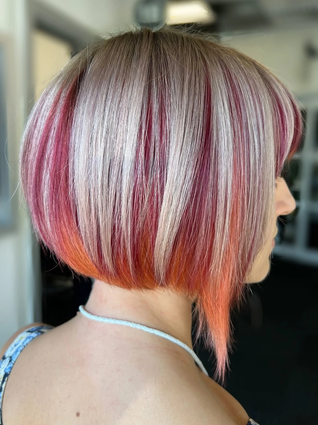 Short silver-rooted bob with vivid red-pink underlayer and pointed nape