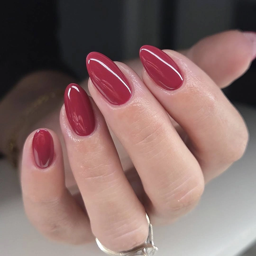 Glossy deep wine red almond nails with a smooth reflective finish