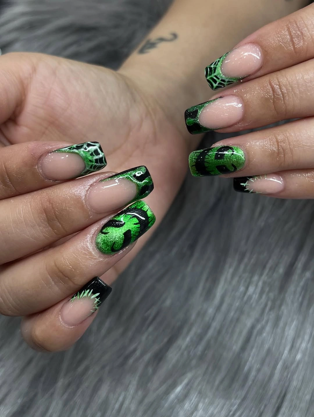 Long square nude nails with black tips bright green webs and spider details