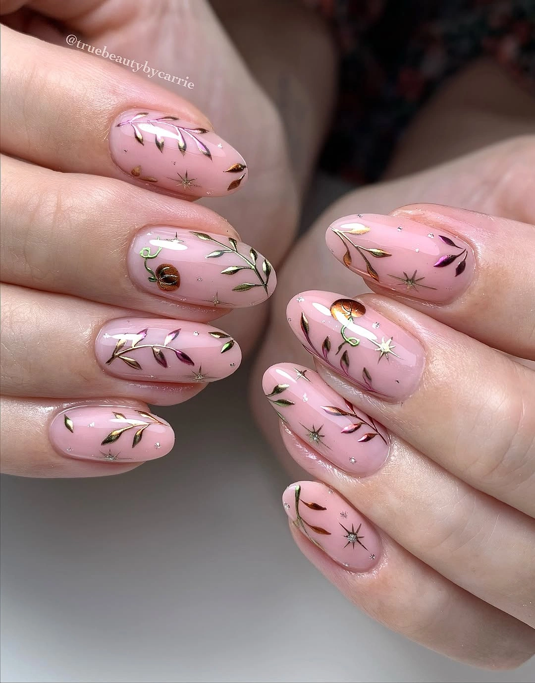 Pale pink almond nails with green leaves stars and small orange details
