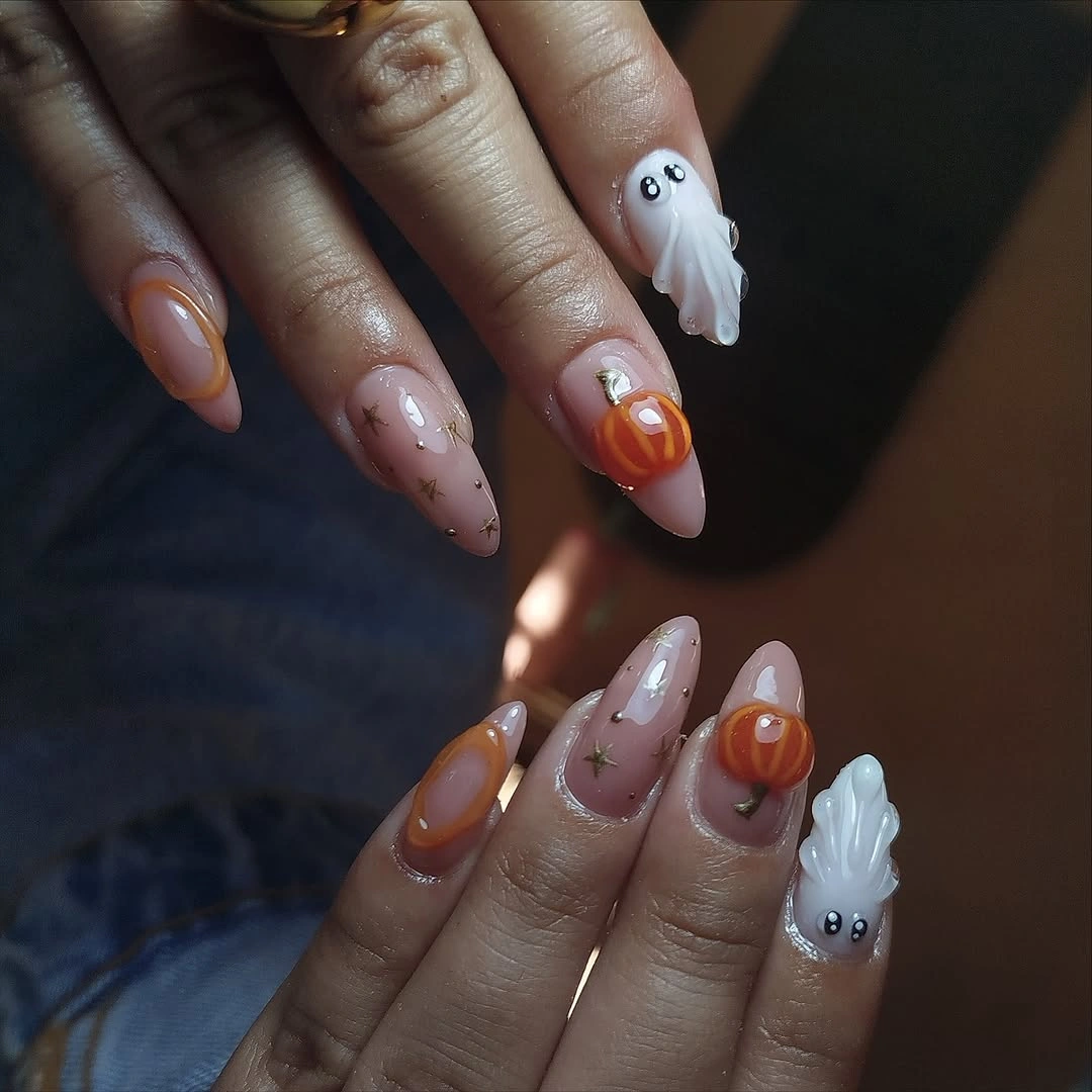 Long pale pink almond nails with pumpkins and raised white ghost accents