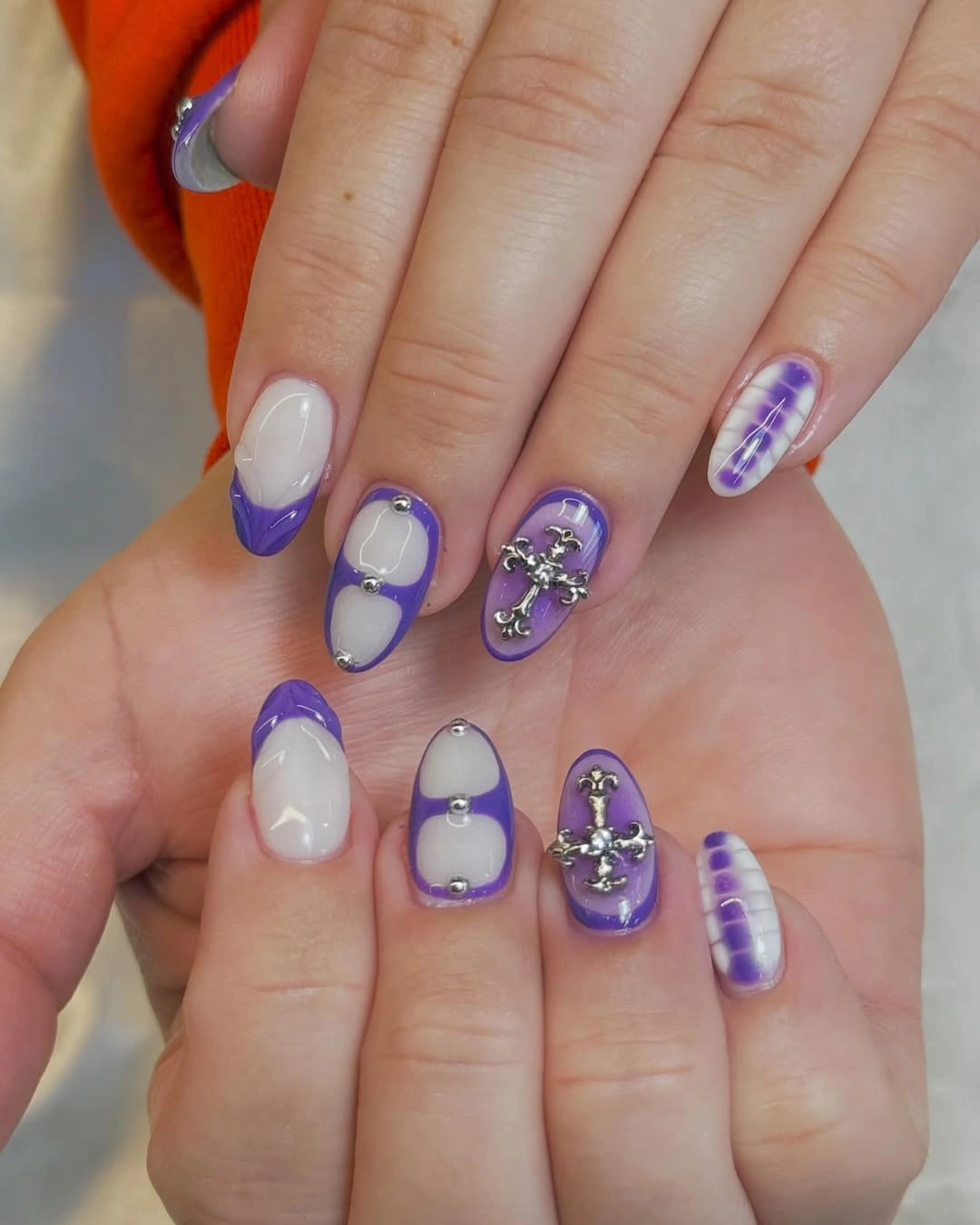 Short square nails with lavender frames silver charms and purple striped accent