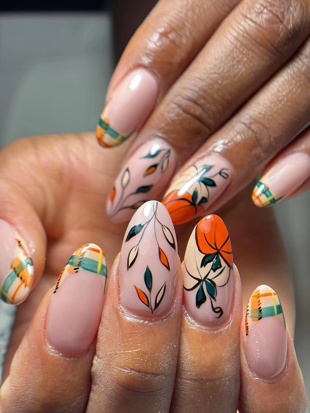 Nude almond nails with orange flowers green leaves and striped tips
