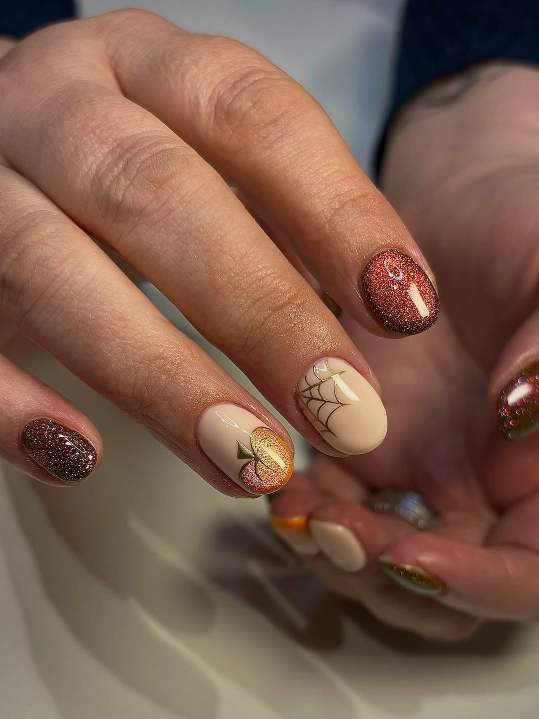Copper glitter nails with cream bases and textured leaf-like accents
