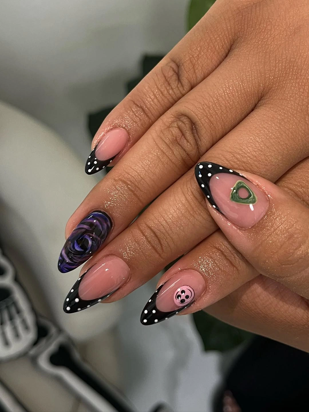 Pale pink almond nails with black polka French tips purple rose and icon accents