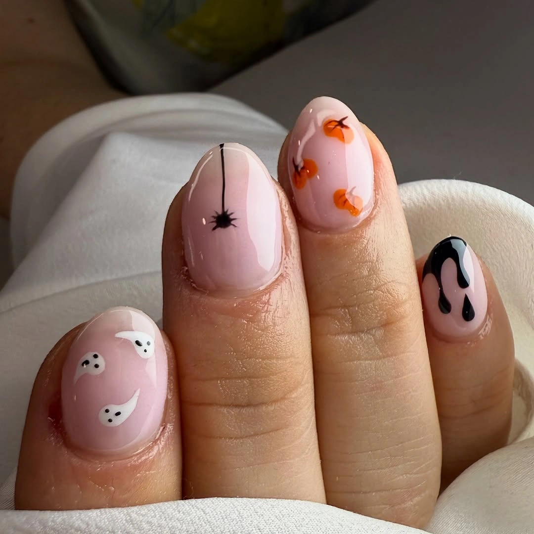 Short pale pink nails with ghosts pumpkins webs and black drips