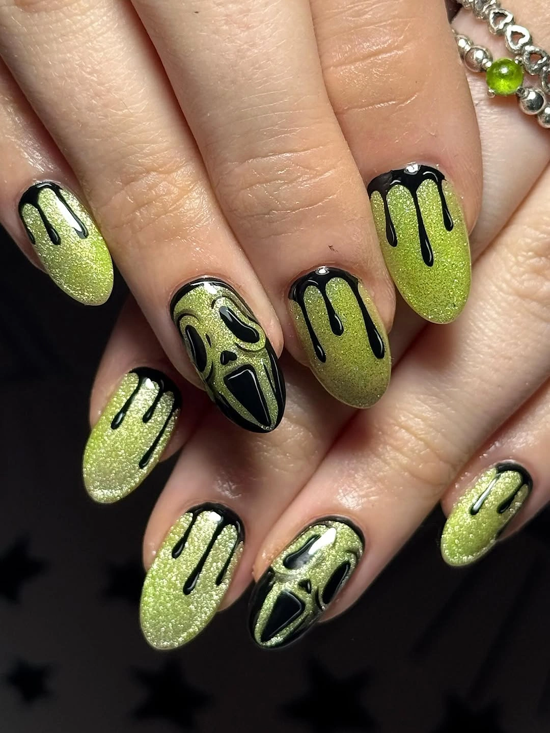 Lime glitter almond nails with black drip tips and face accent