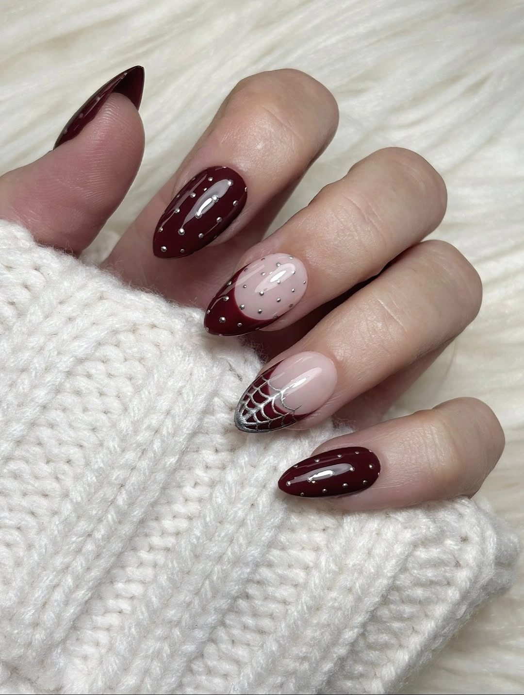Glossy burgundy nails with pale pink spiderweb accent nails