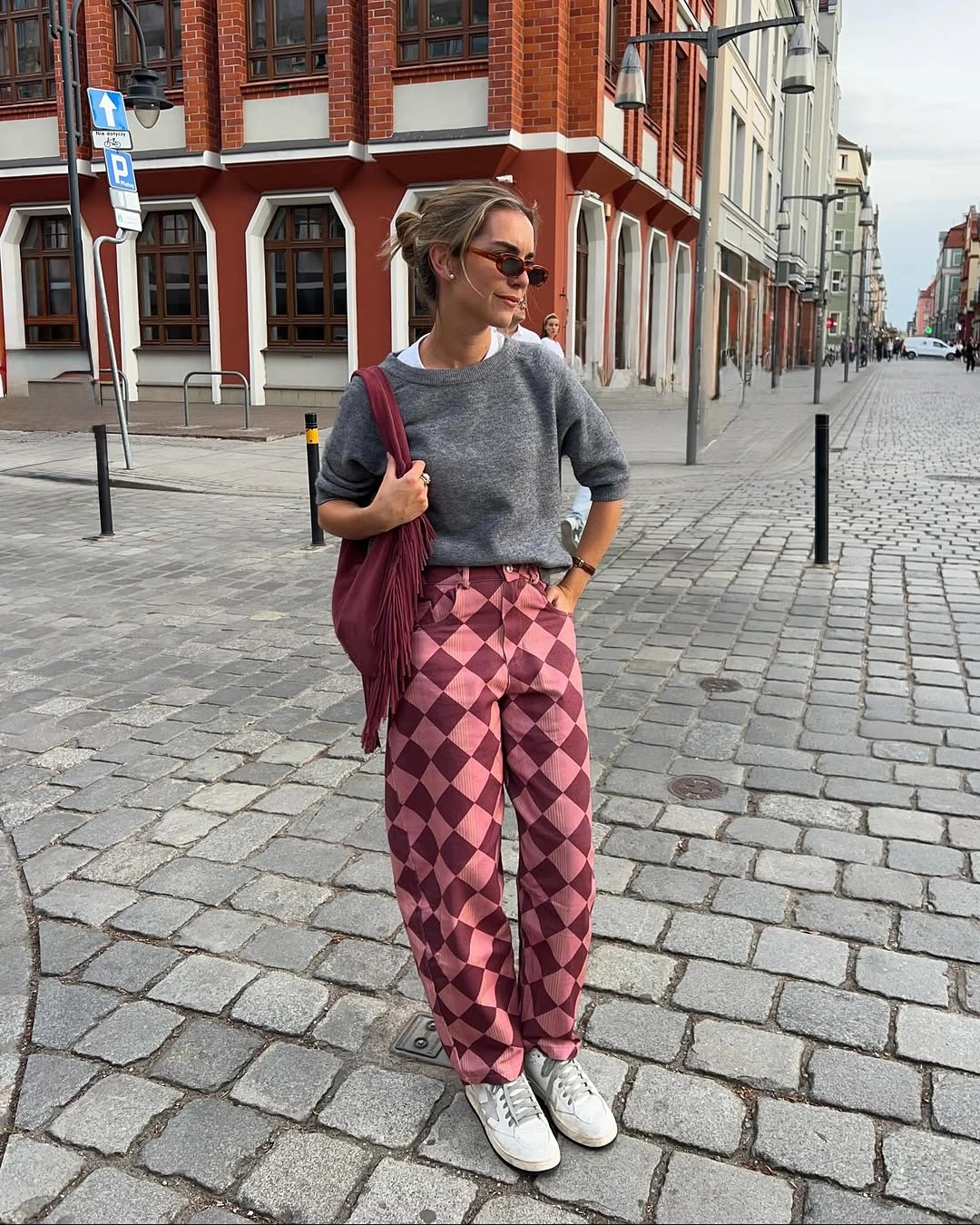 Gray sweater with pink argyle trousers white sneakers and burgundy bag