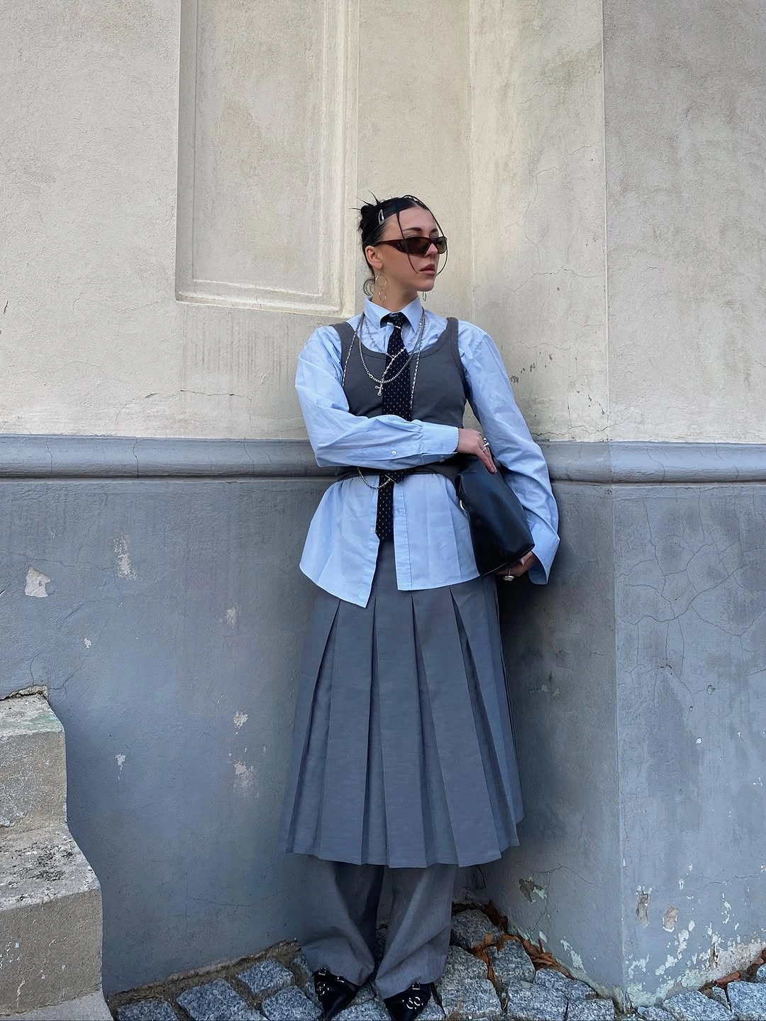 Blue button shirt with dark vest and gray pleated midi skirt