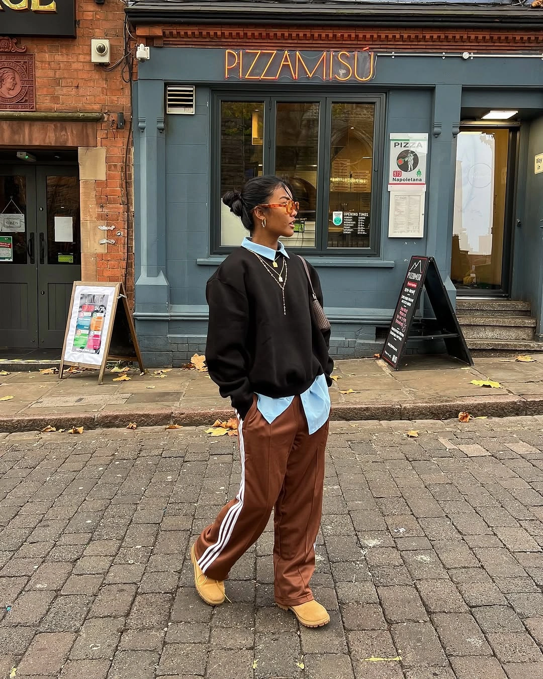 Black sweatshirt layered over blue shirt with brown striped trousers