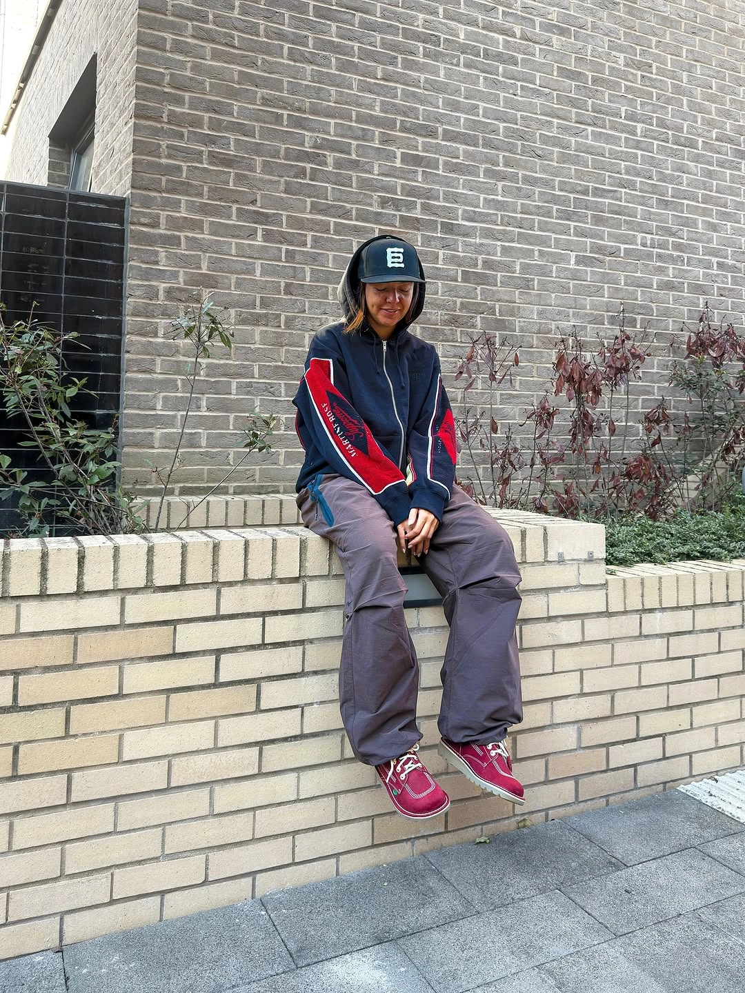 Navy and red panel hoodie with gray cargo trousers and red sneakers