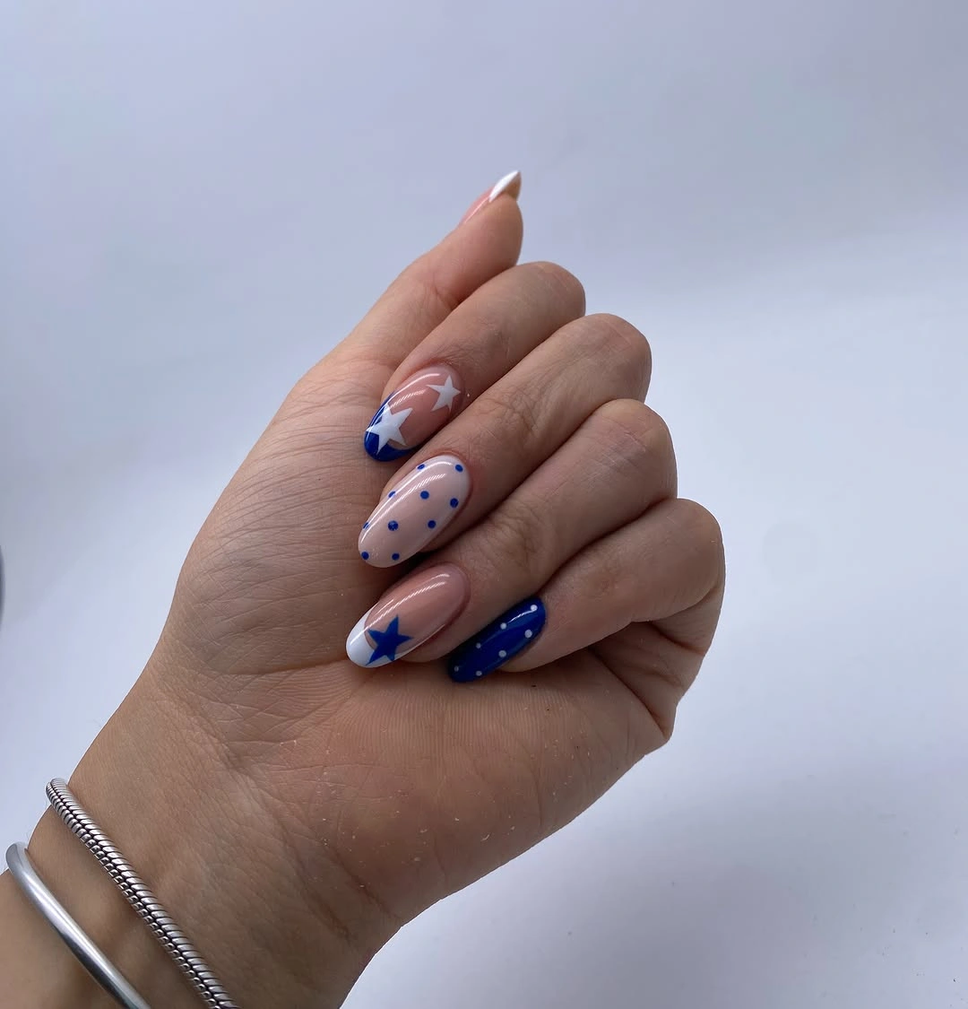 Nude almond nails with cobalt blue dots and white accent details