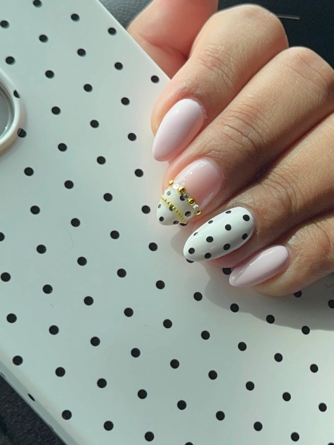 White almond nails with black dots and a small yellow floral accent