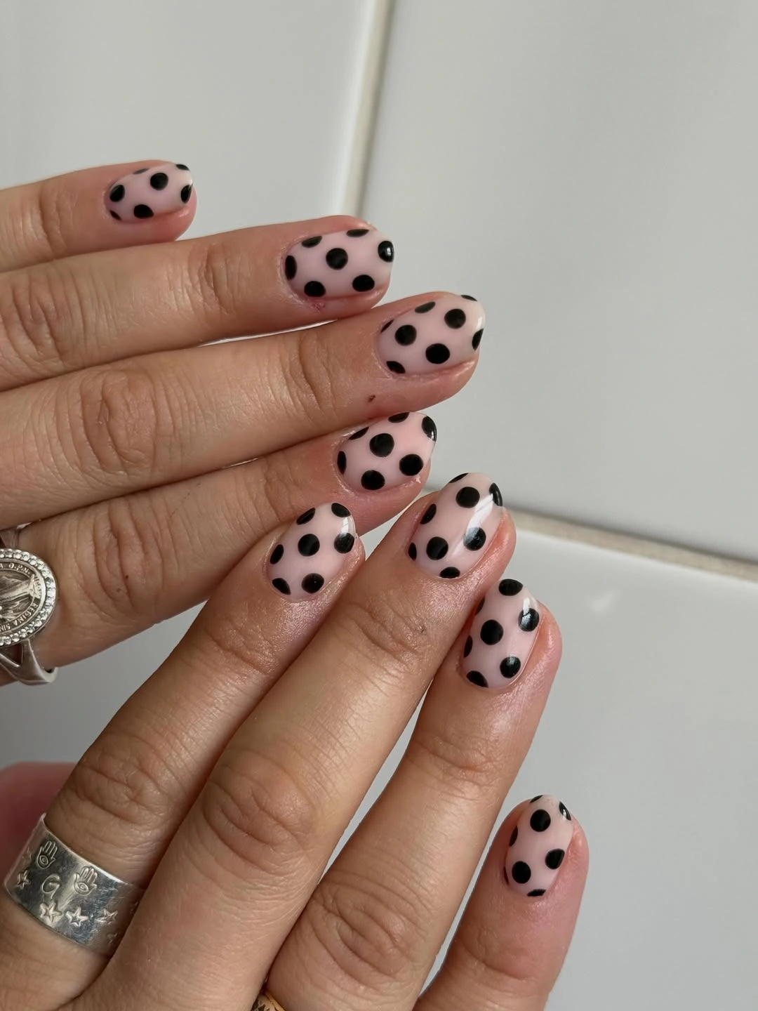 Pale pink oval nails with oversized evenly spaced black polka dots