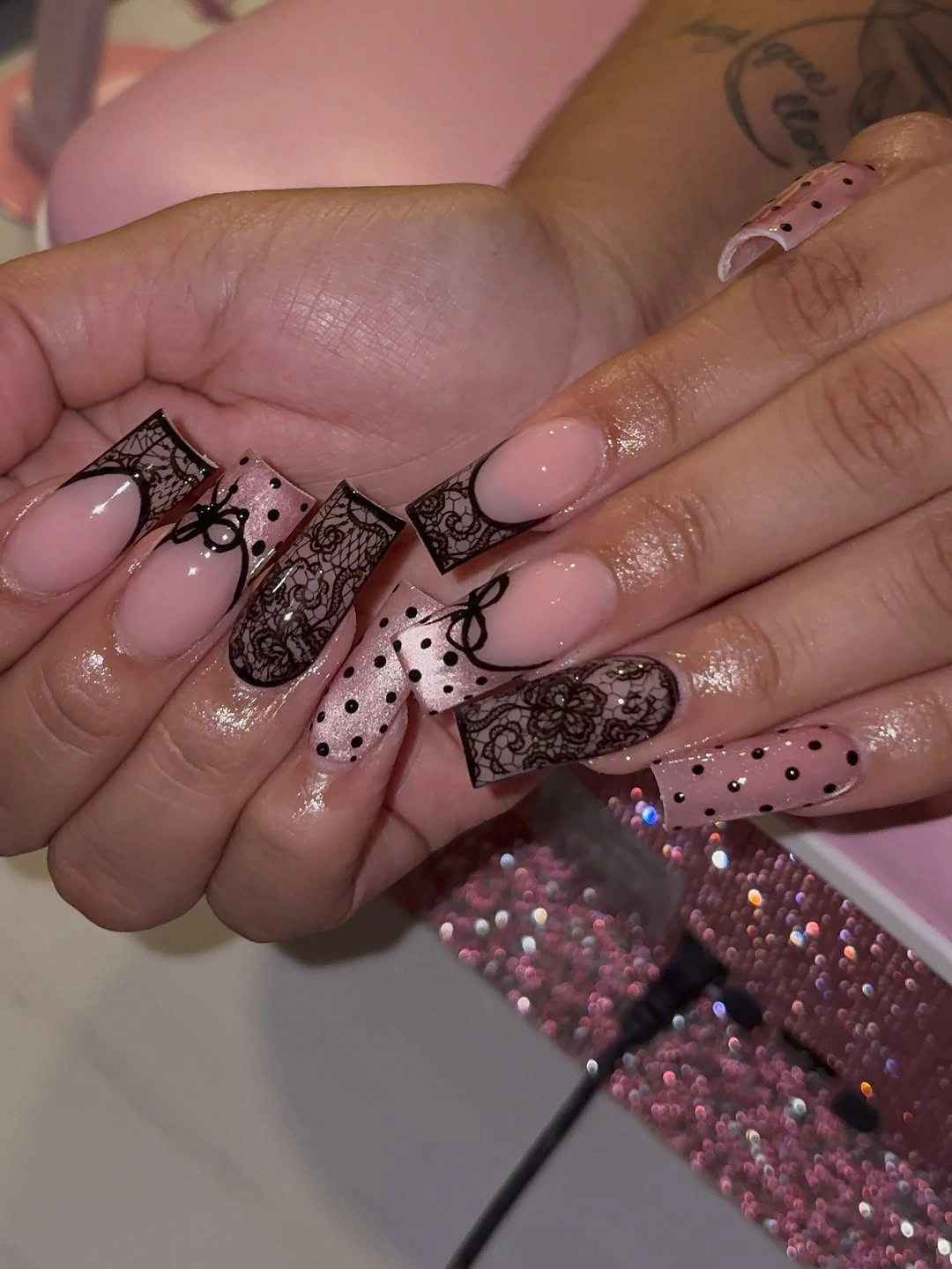 Long nude square nails with ornate black dotted and lace like panels
