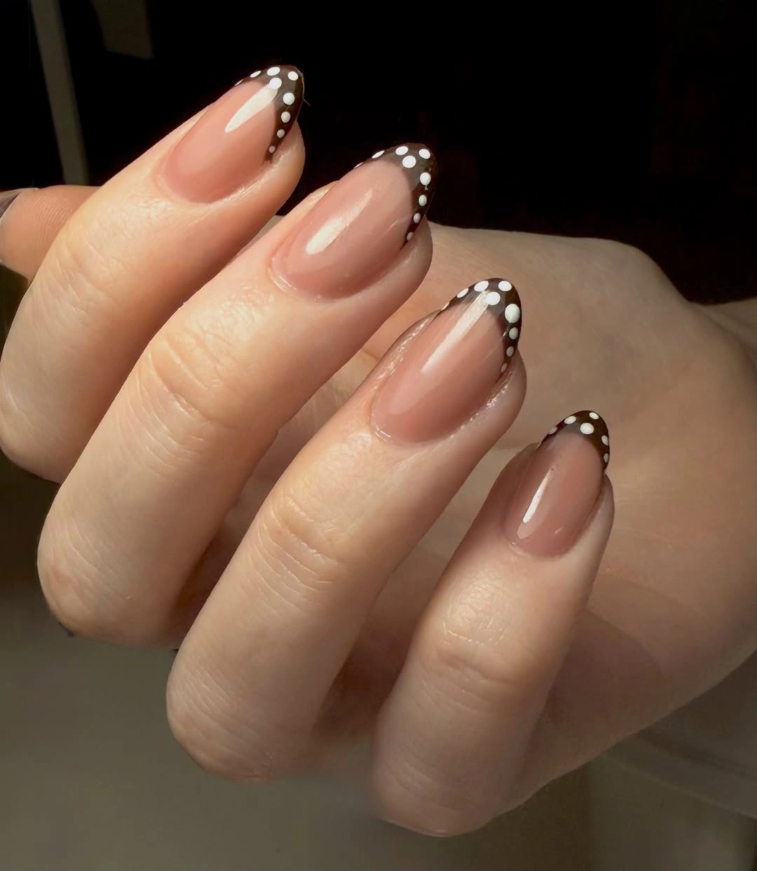 Nude almond nails with black tips edged by small white dots