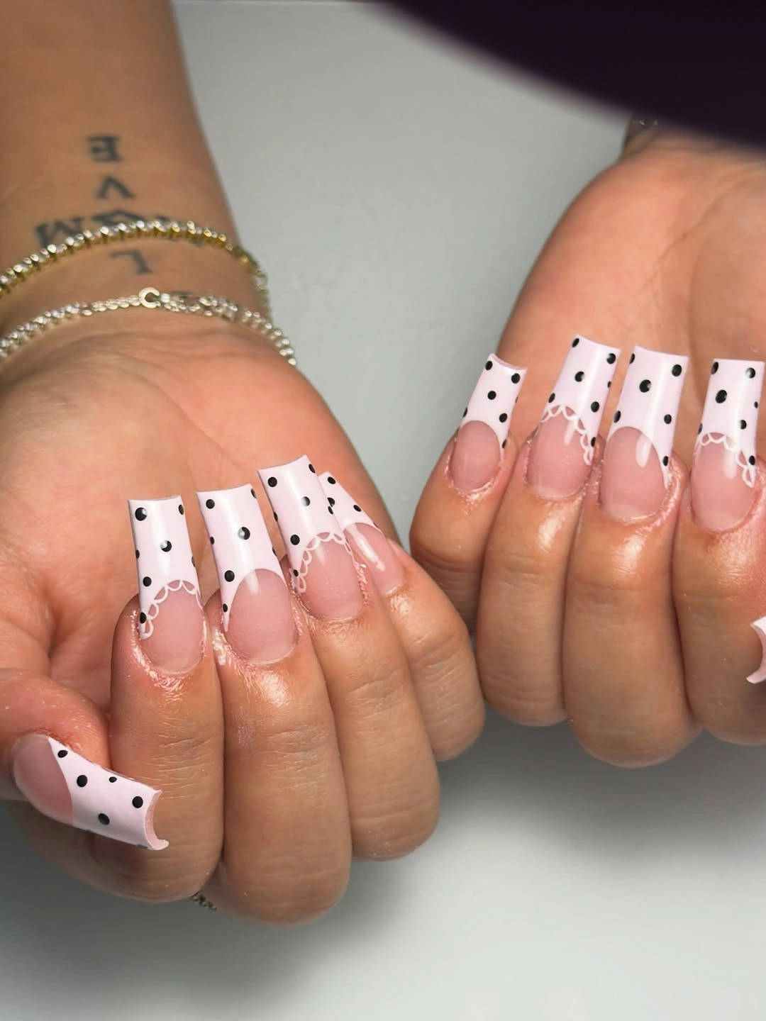 Long nude square nails with broad white tips and black dots