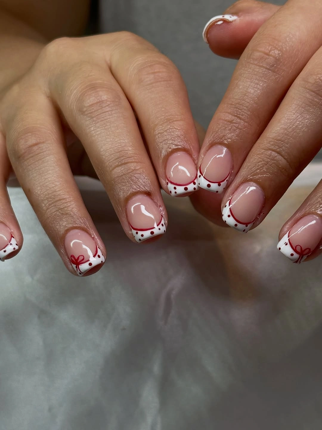 Short nude and white nails with burgundy dots and heart like outlines