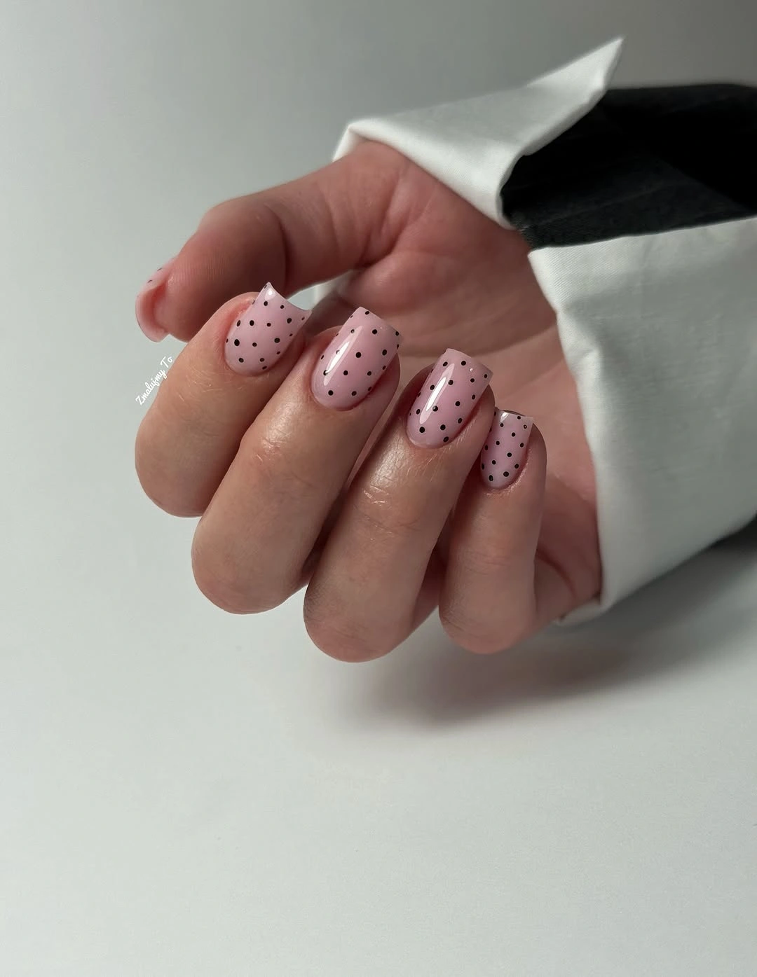 Dusty pink short oval nails with evenly spaced small black dots