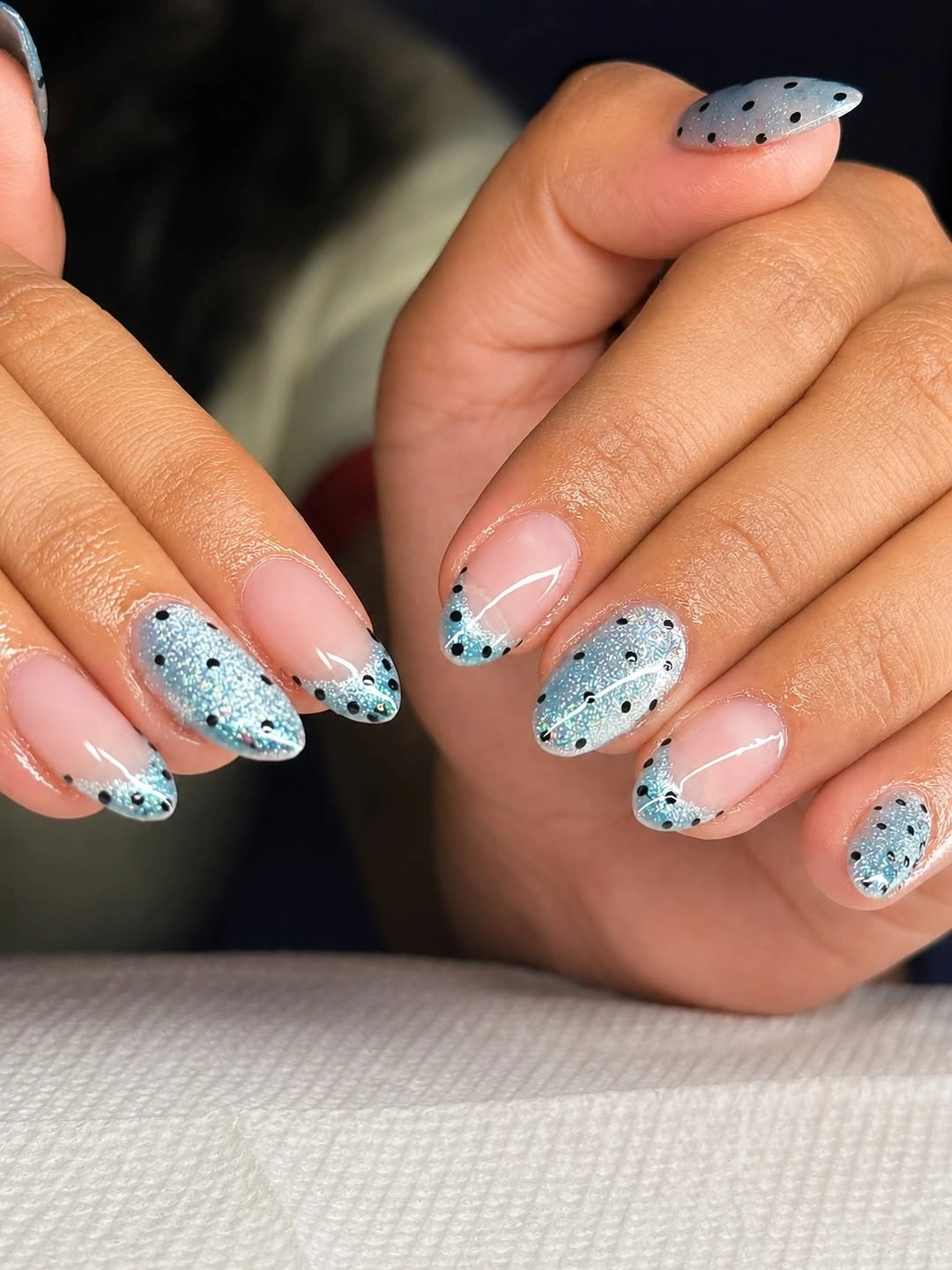 Nude almond nails with pale blue tips and tiny black dots