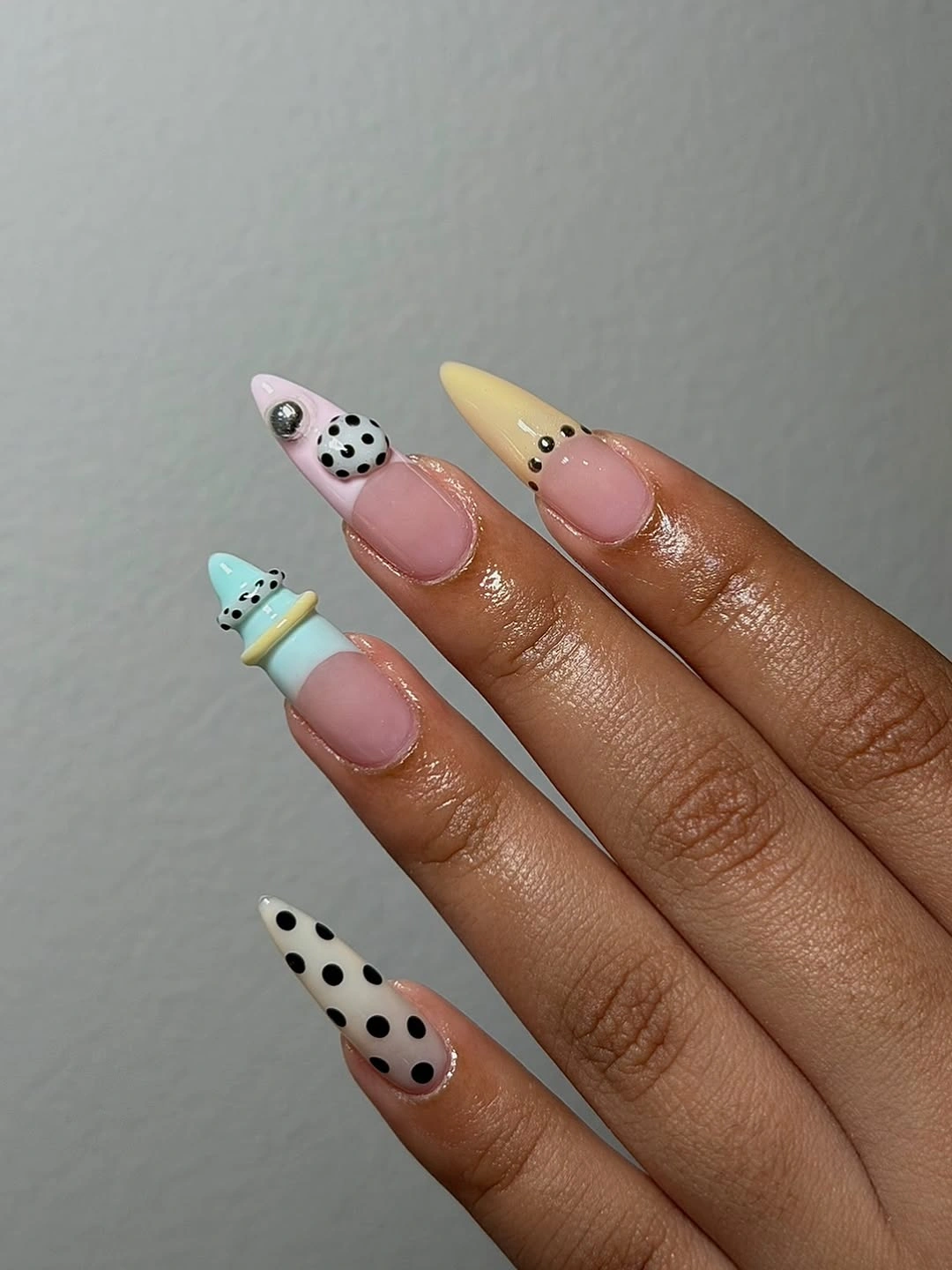 Nude almond nails with pastel multicolor tips and black polka dots