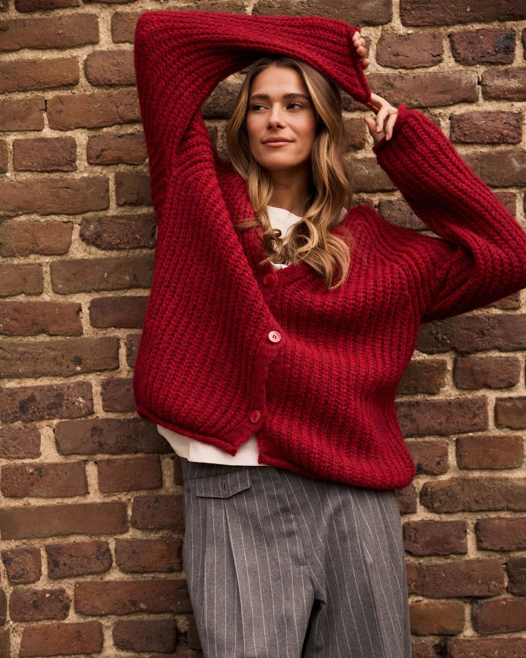 Oversized red knit cardigan with gray striped trousers