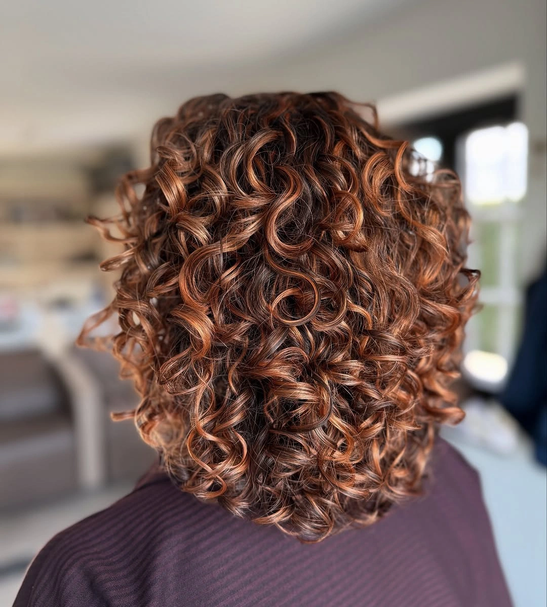Defined brown curls with warm dimensional highlights