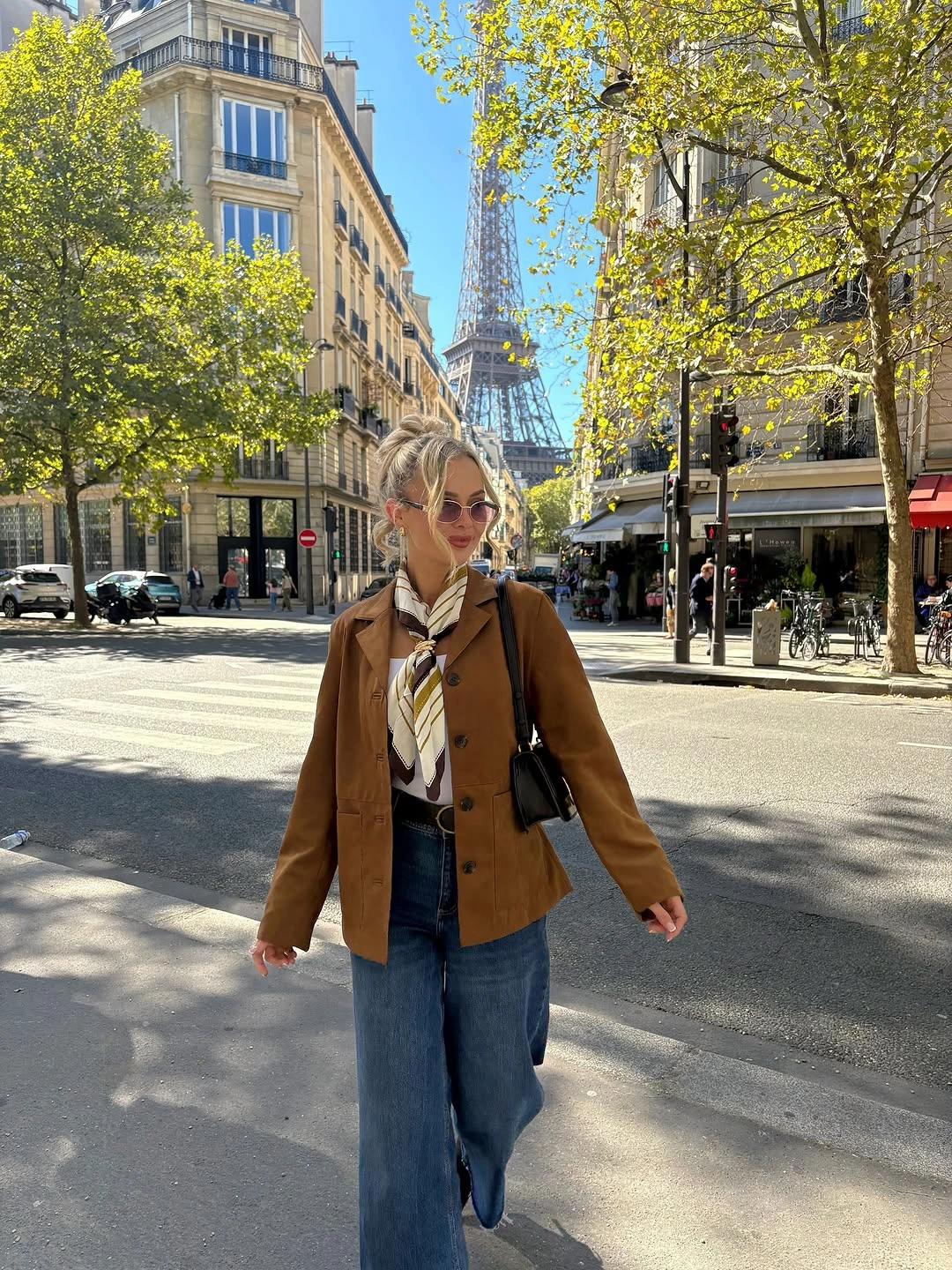 Brown jacket blue jeans and a small neck scarf