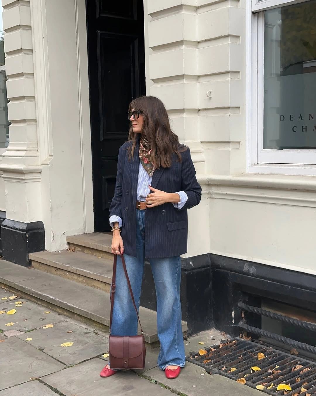 Navy blazer flared jeans red flats and brown bag