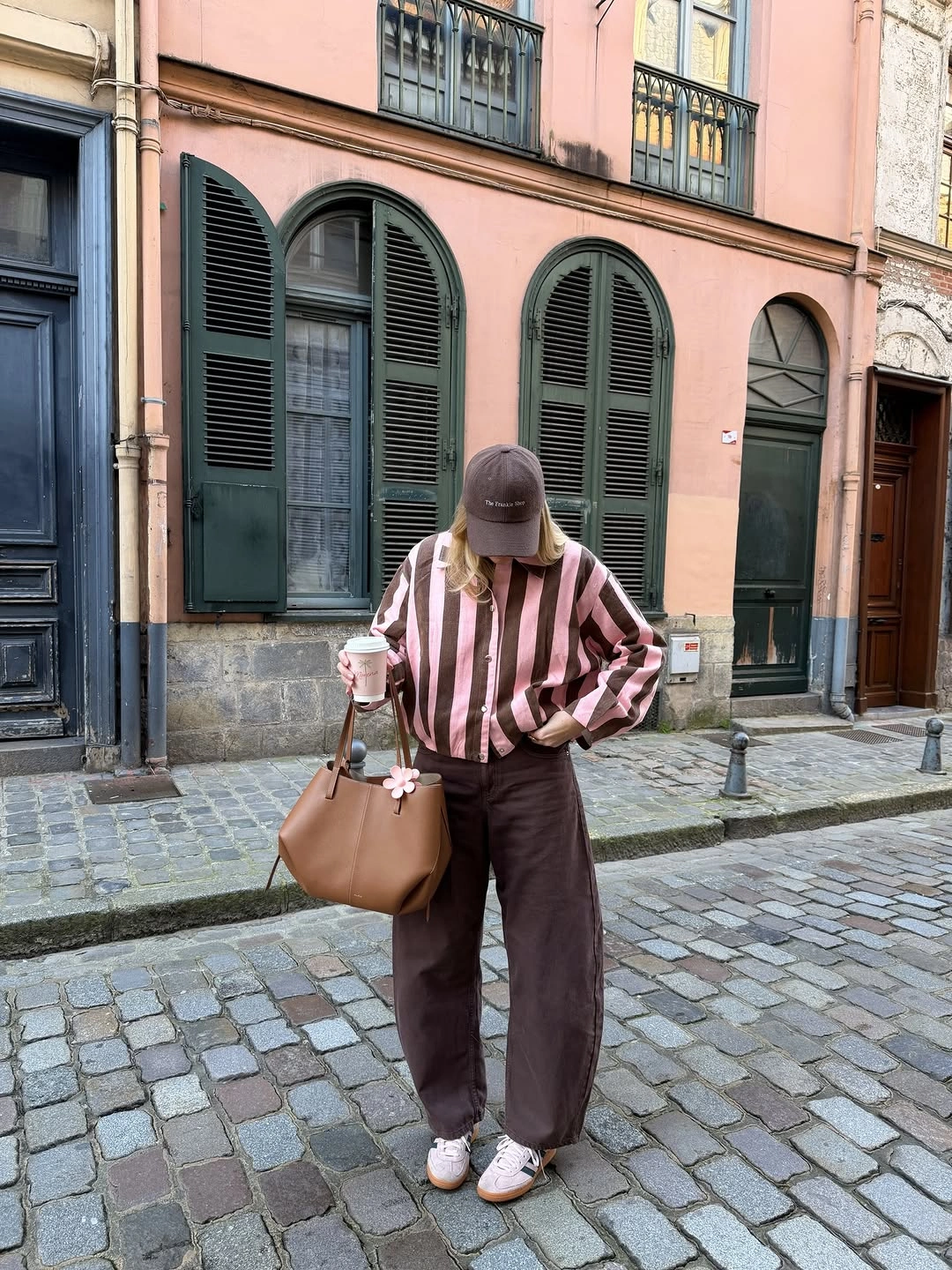 Burgundy striped sweater dark trousers cap and sneakers