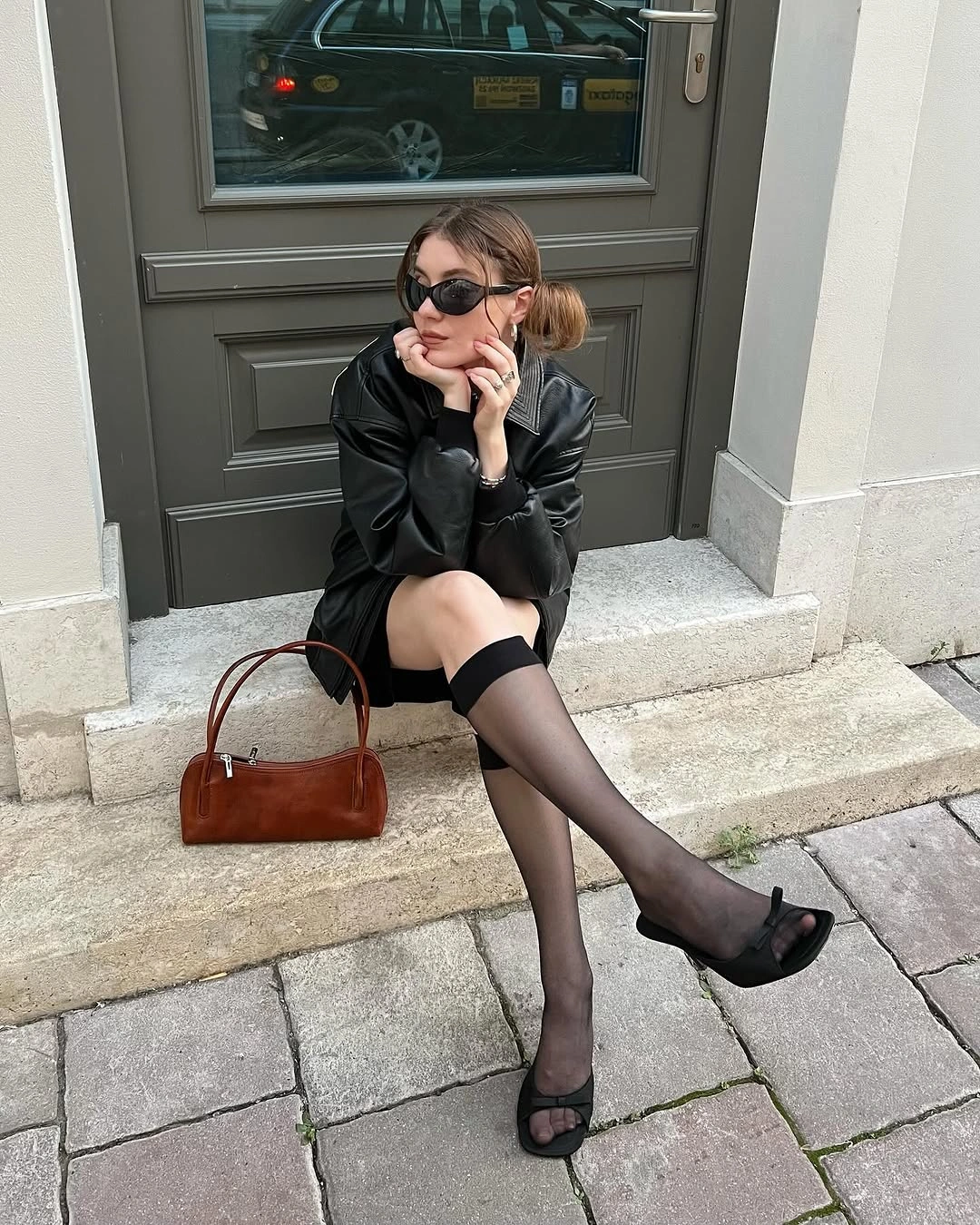 Black jacket shorts tights pointed shoes and brown bag