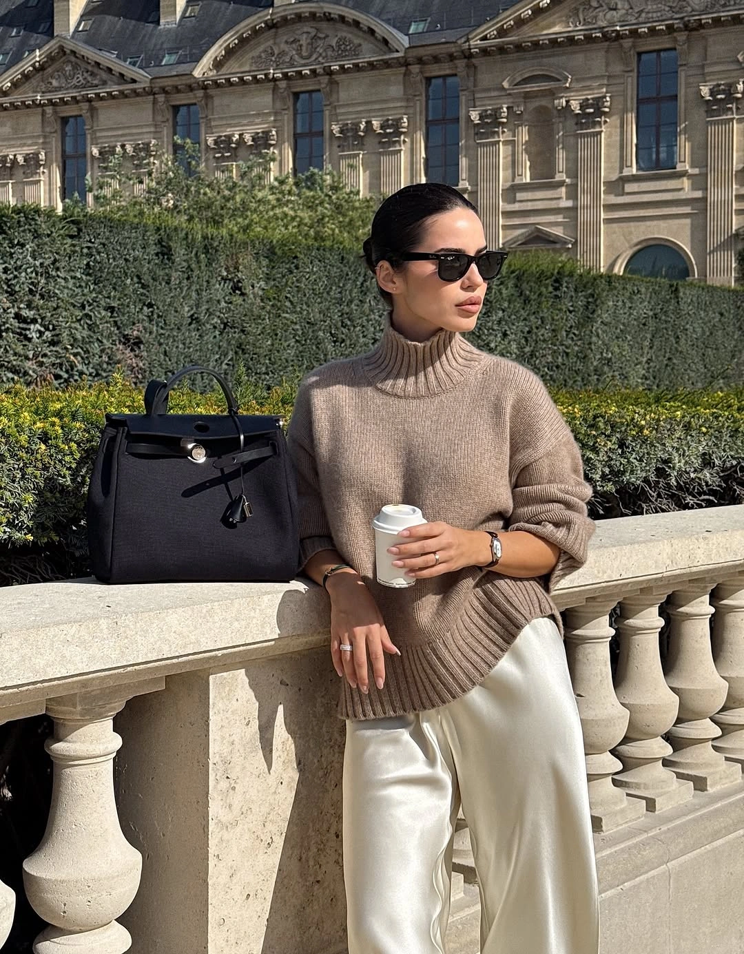 Taupe turtleneck with white trousers and black bag