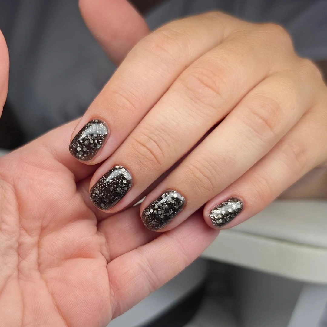 short charcoal nails covered with concentrated silver sparkle
