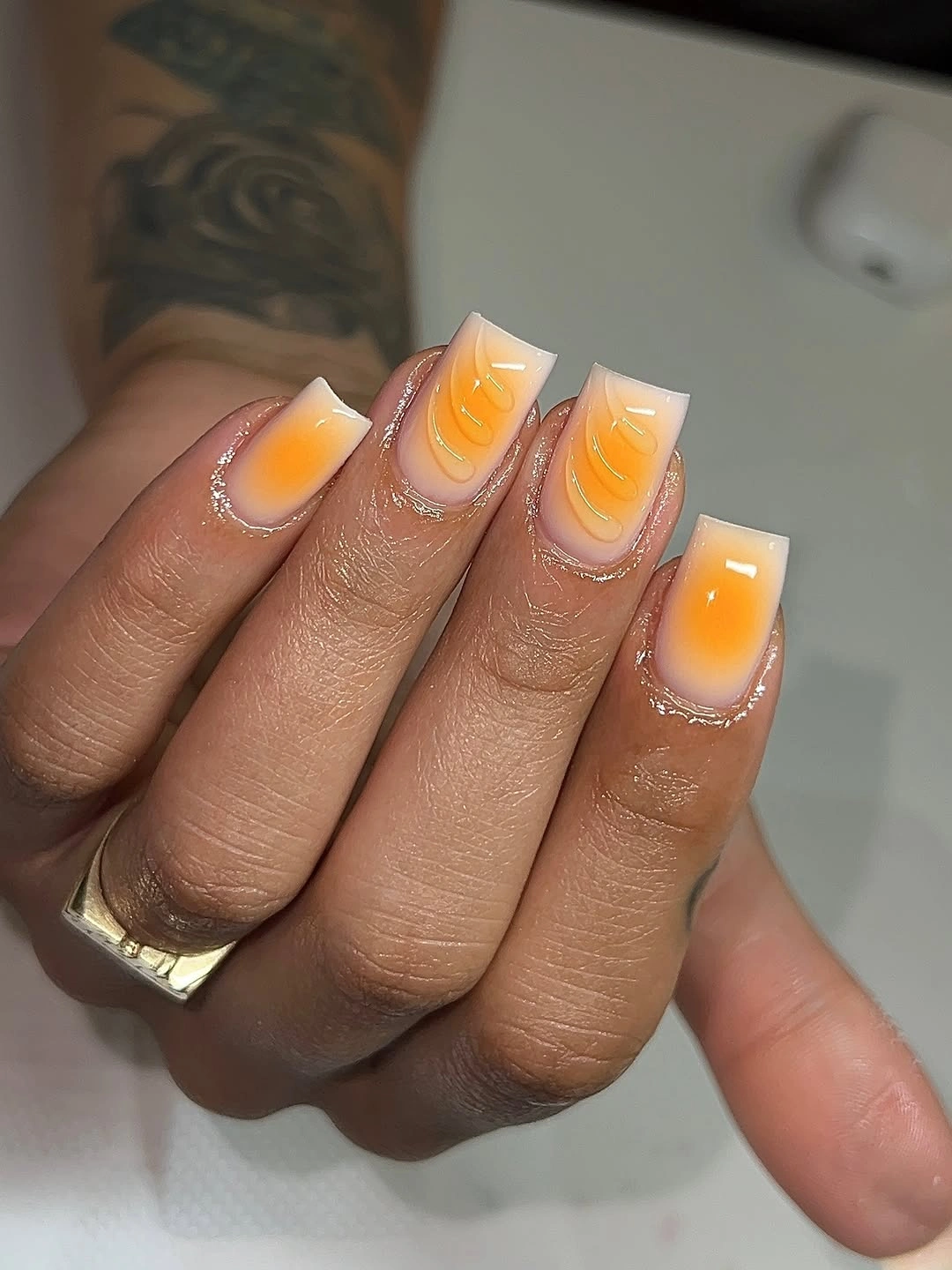 short bright orange nails with lighter yellow curved swirls