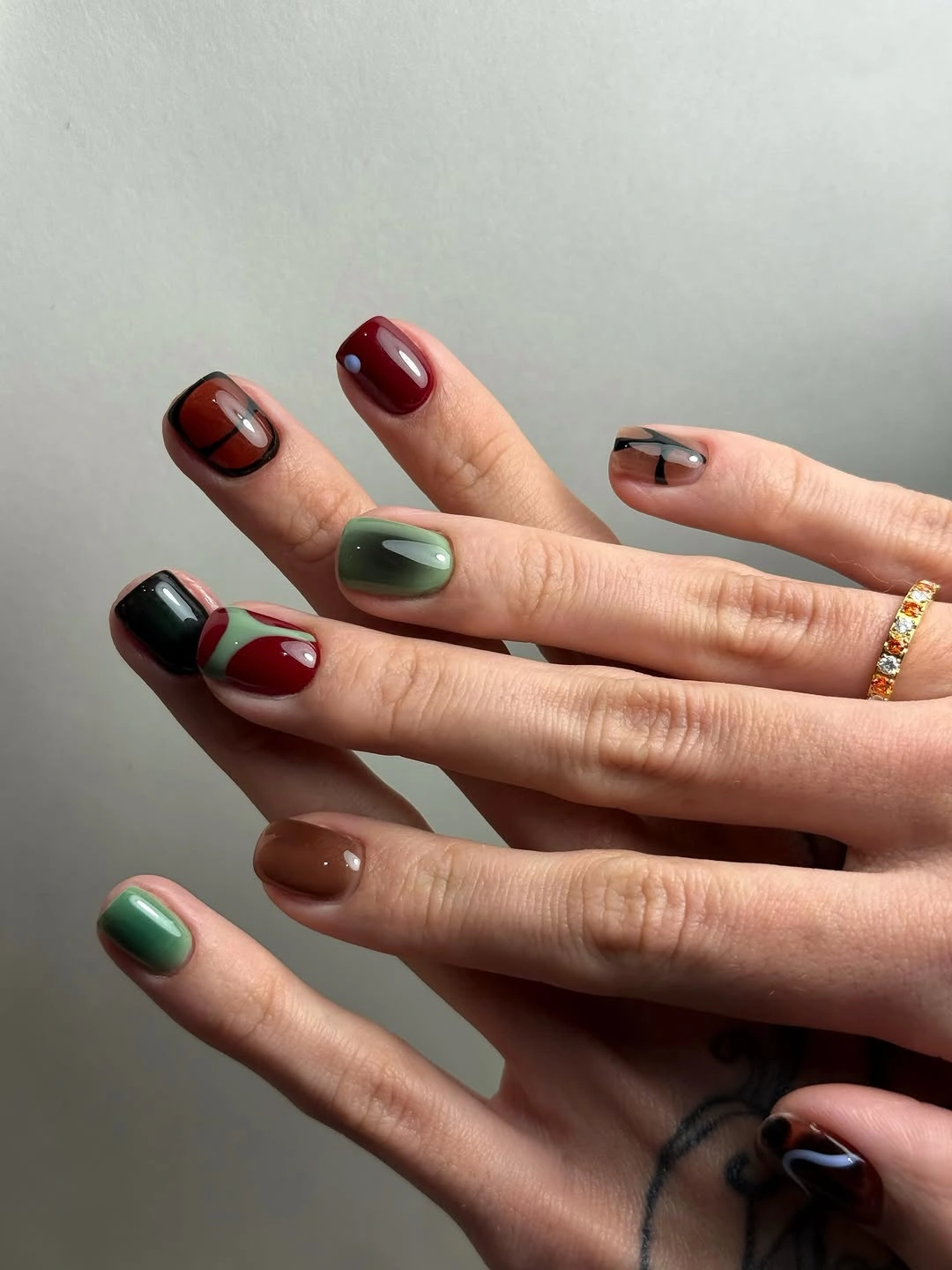 short mixed-color nails in muted brown green burgundy and pink