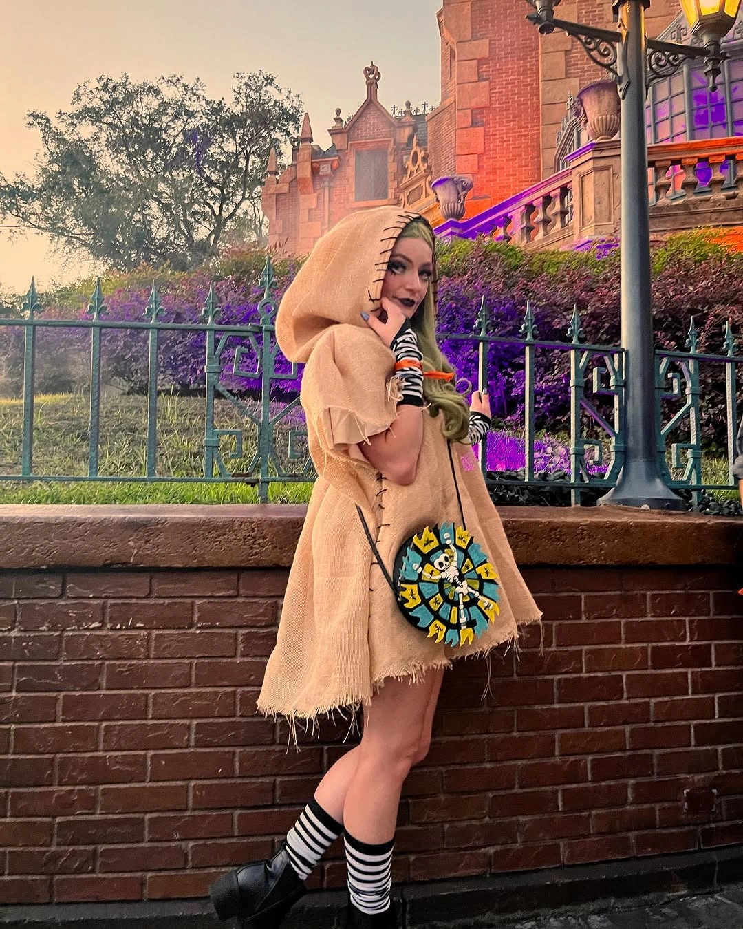 Tan hooded short dress with striped socks black shoes and round printed bag