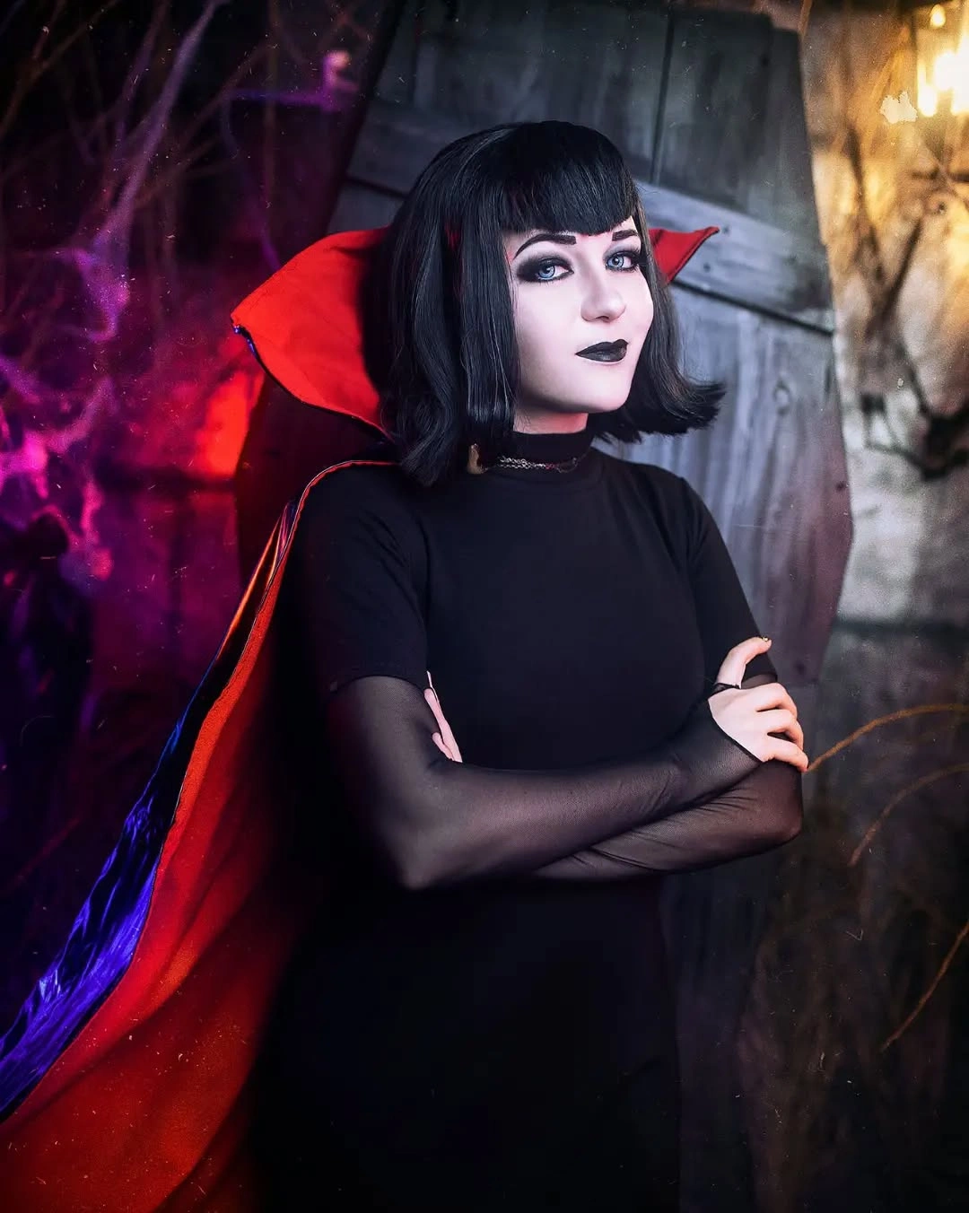 Black fitted high-neck dress with red-lined cape pointed red collar and black mesh gloves