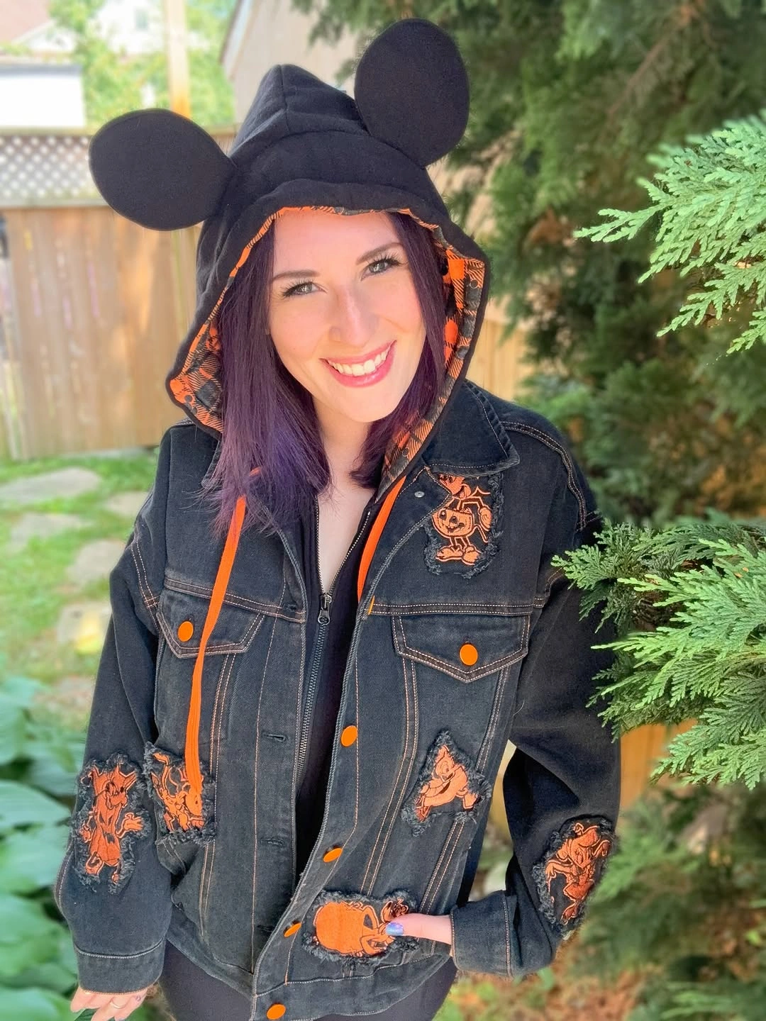Dark denim jacket with orange pumpkin-style embroidery and black round-ear hat with orange trim
