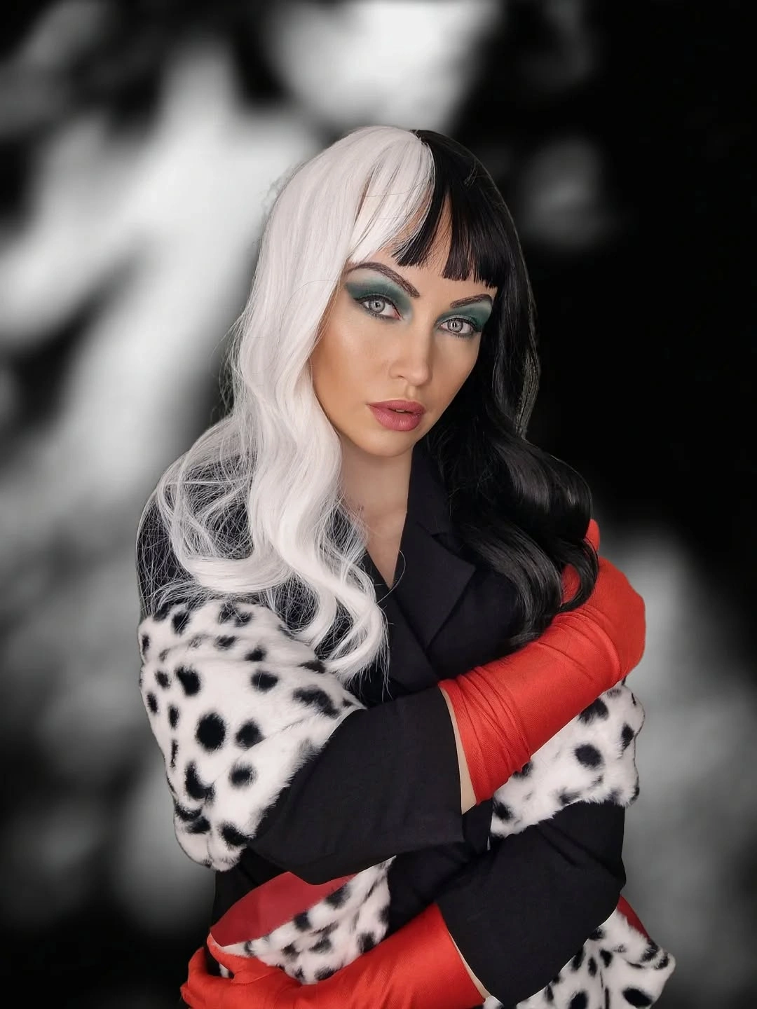 Black fitted coat with black-and-white spotted trim and red gloves