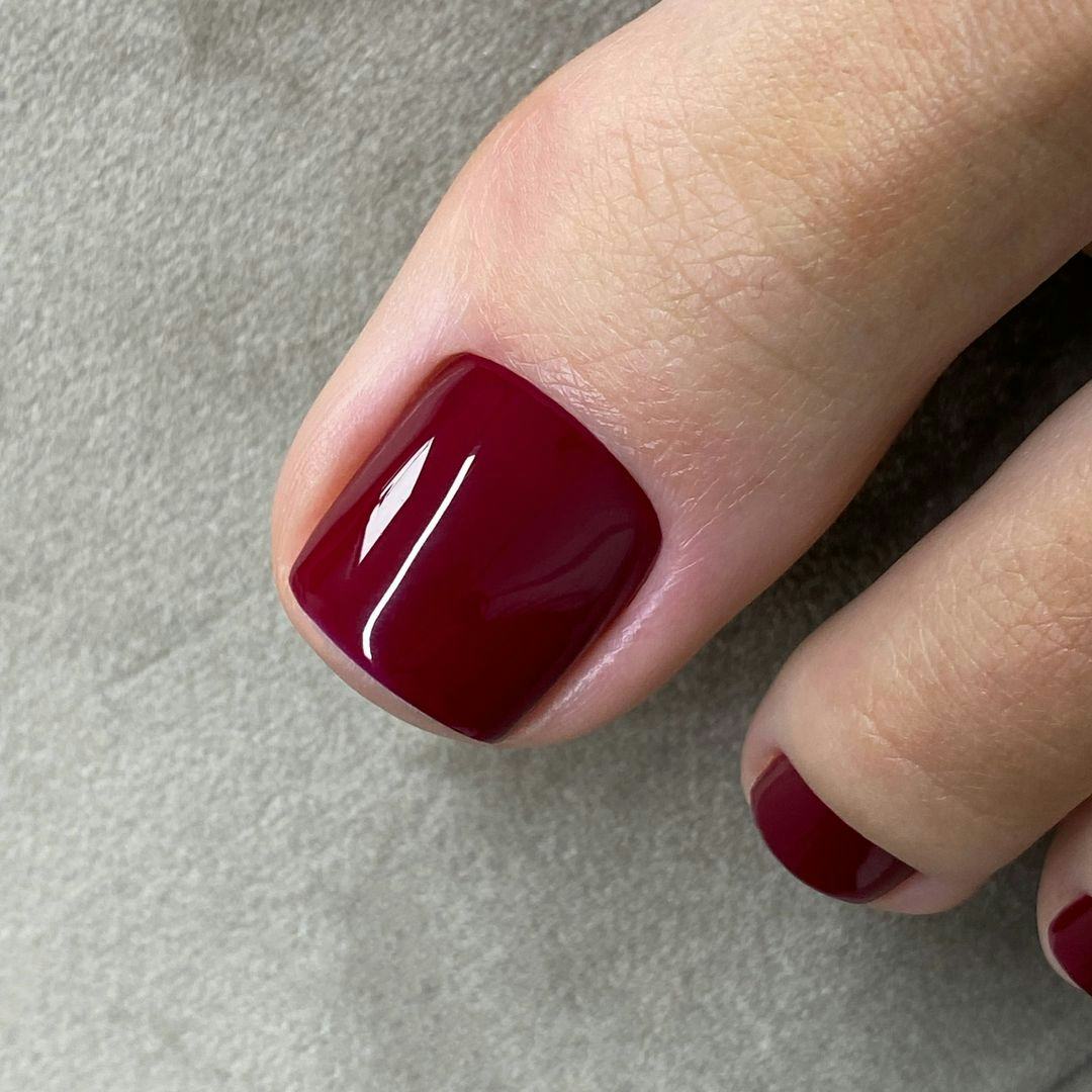 Close-Up Of One Foot Deep Red Glossy Toenails Close-Up Of One Foot Deep Red Glossy Toenails — Winter Toe Nails