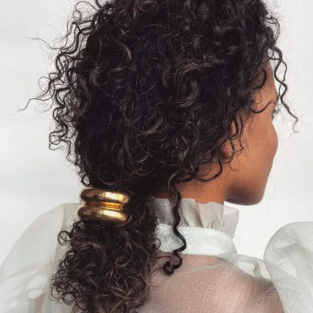 Low Ponytail with Gold Accessory — Winter Hairstyles for Curly Hair