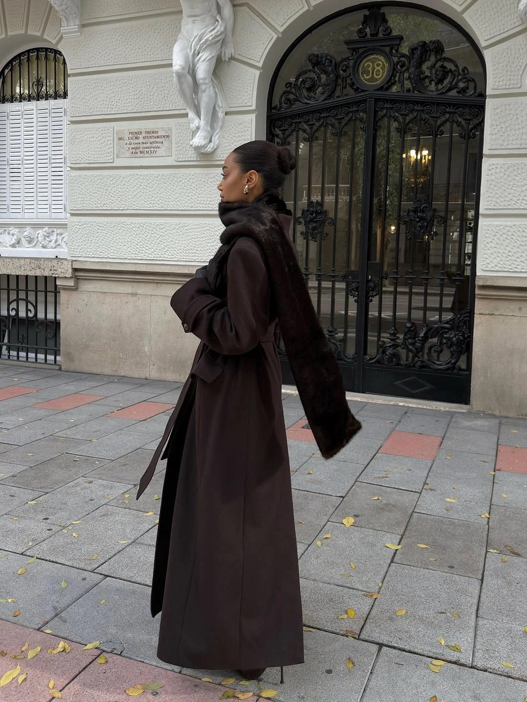 Long dark brown coat wide scarf black boots and dark sunglasses