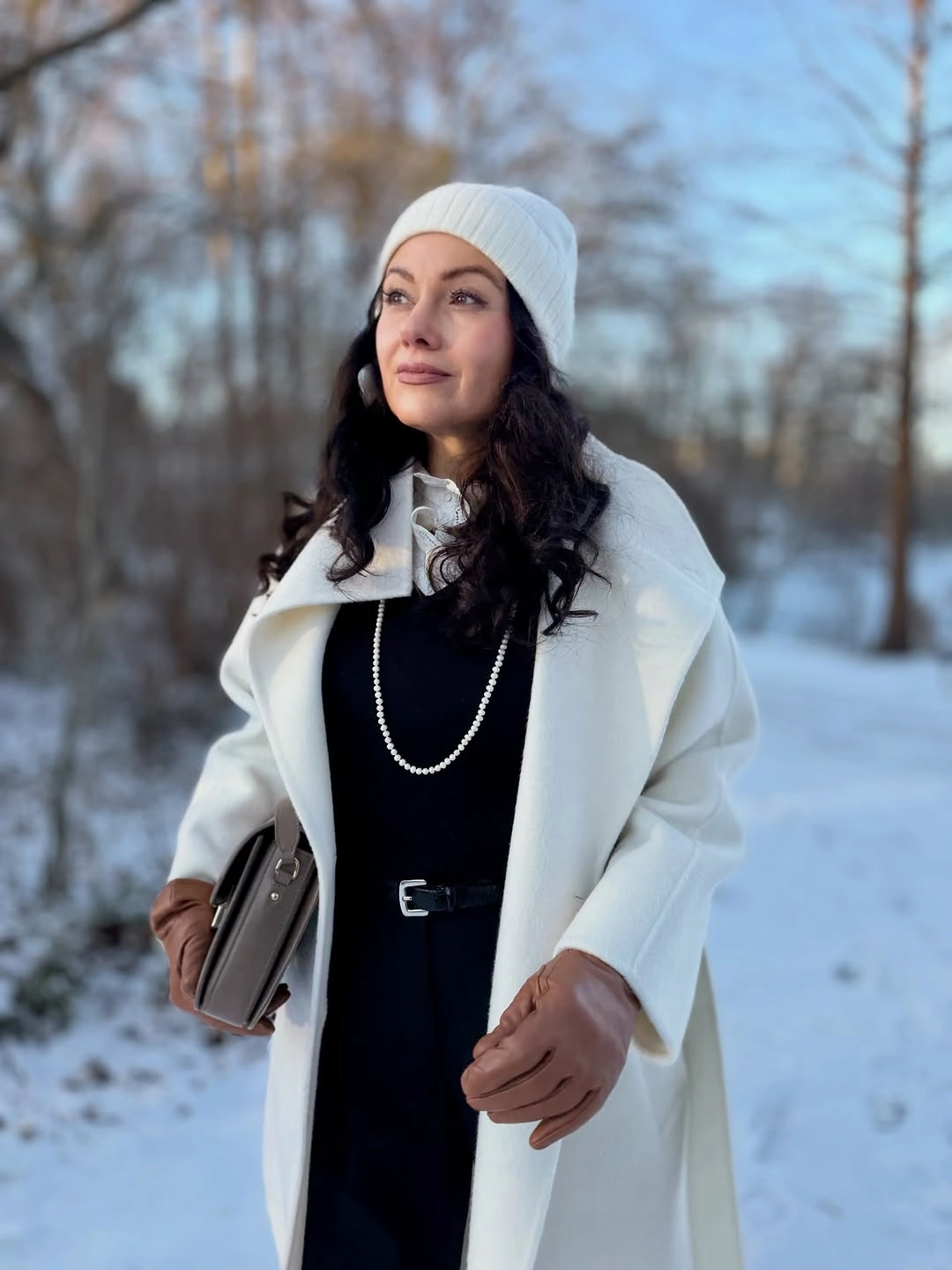 White long coat black inner outfit white knit hat necklace and brown shoulder bag