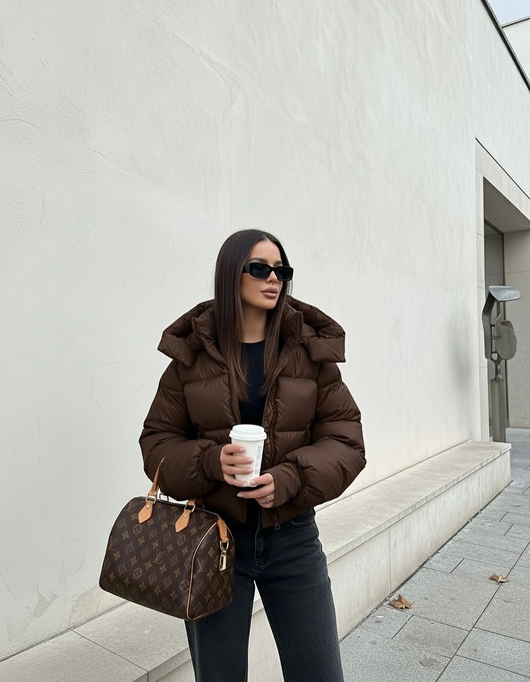 Brown puffer black top dark straight jeans sunglasses and brown handbag