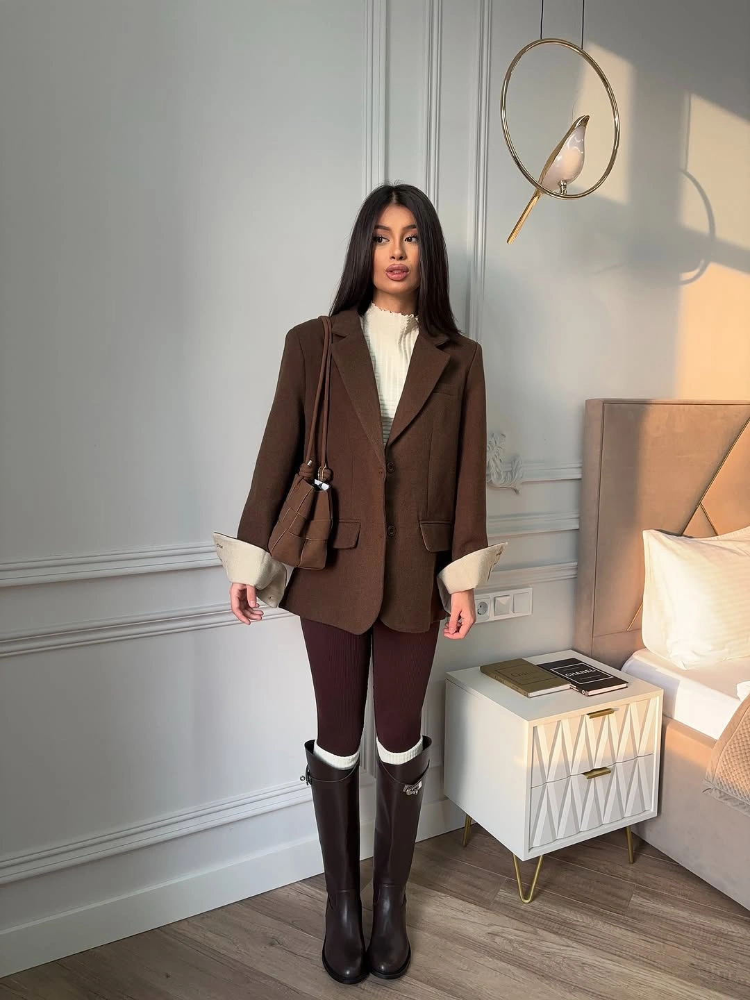 Brown blazer white high neck top burgundy trousers tall dark boots and brown bag
