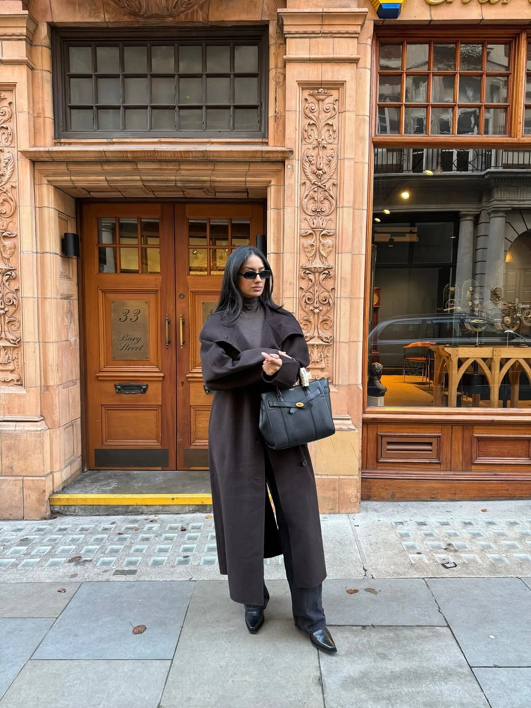Charcoal hooded long coat dark boots sunglasses and structured black handbag