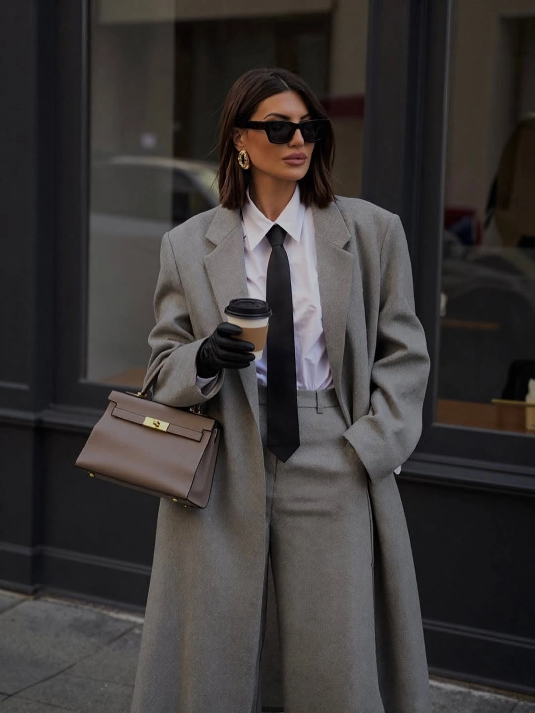 Gray tailored coat white shirt black tie gloves and taupe structured bag